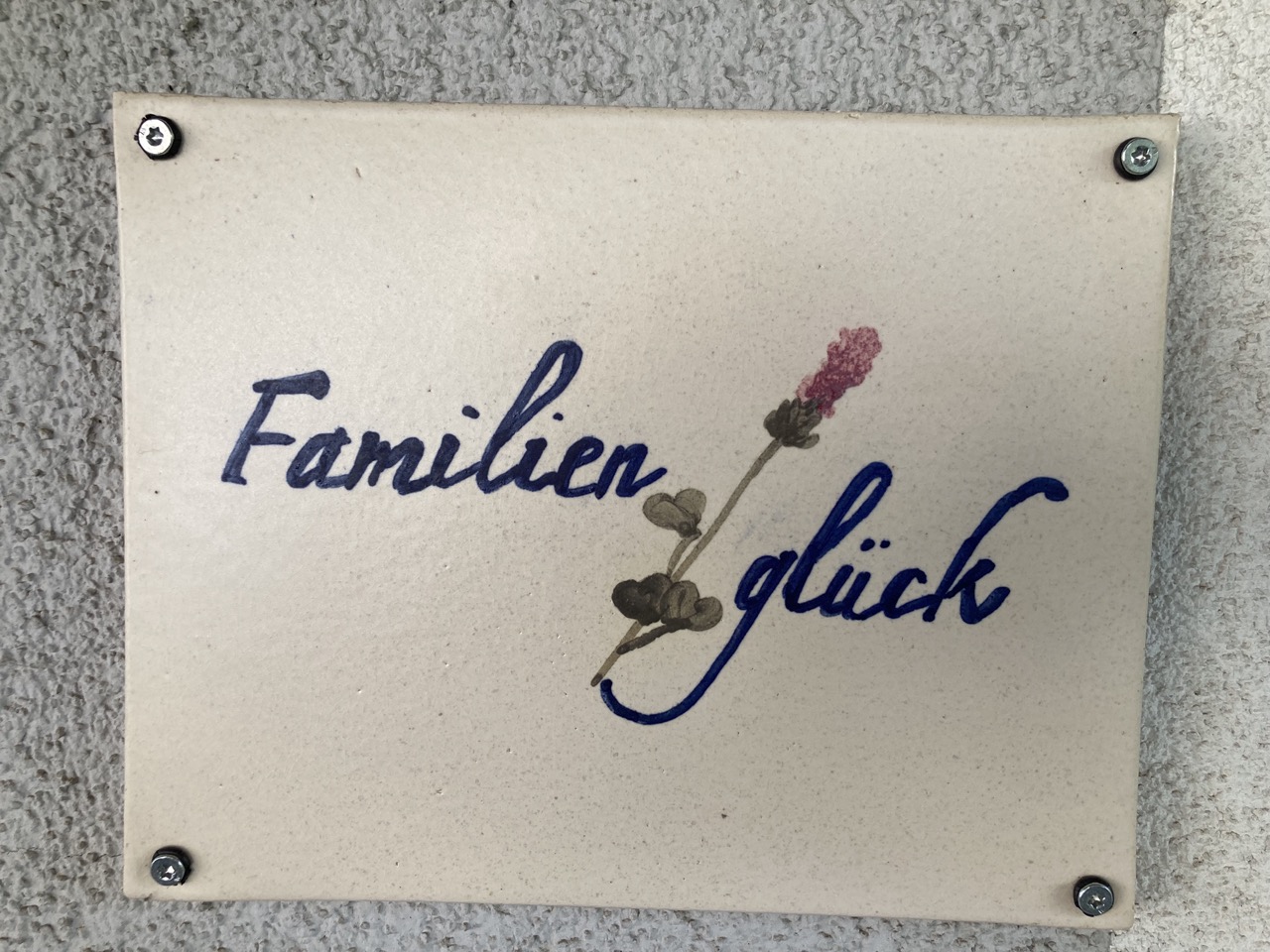 Freundliche Begrüßung am Eingang mit einem Türschild aus Keramik und dem Namen der Wohnung Familienglück.