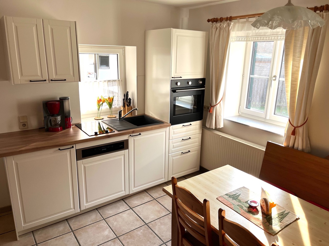 Vollwertige helle Küche im Landhausstil mit Essplatz und zwei Fenstern. Es gibt auch ein Sofa.