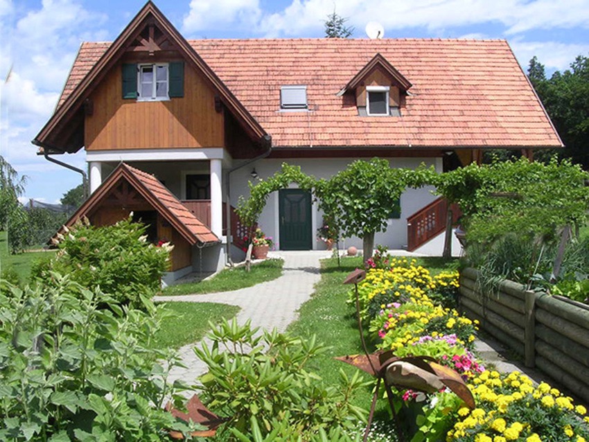 Schönes Ferienhaus umgeben mit einem Hochbeet und bunten Blumen in ruhiger Lage.
