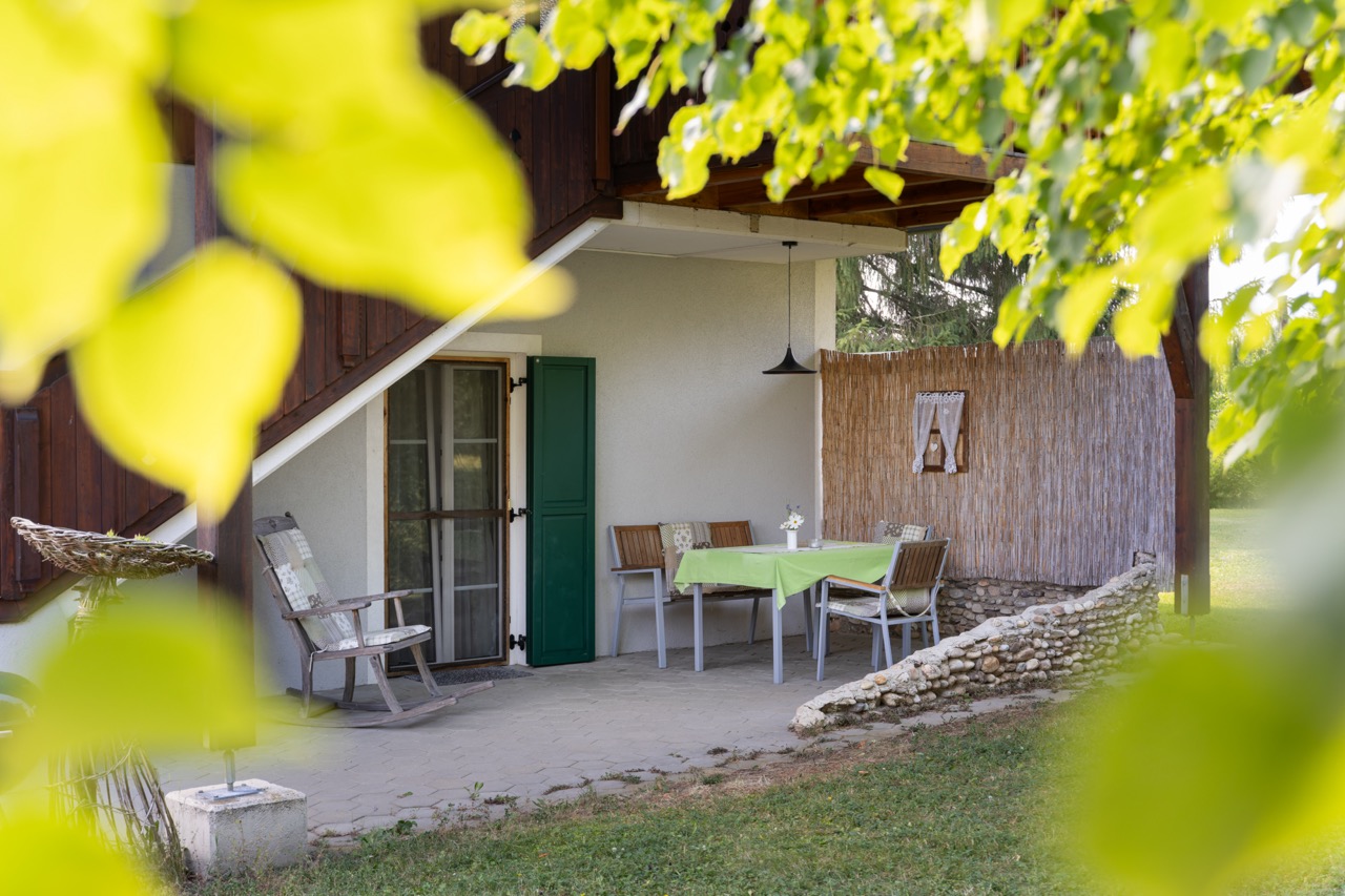 Große, überdachte Terrasse mit Tisch und Stühlen. Es gibt auch einen gemütlichen Schaukelstuhl.