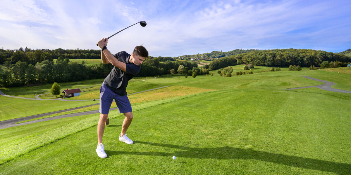 Golfer beim Abschlag auf einem Golfplatz in der sanften Hügellandschaft des Thermen- und Vulkanlands.