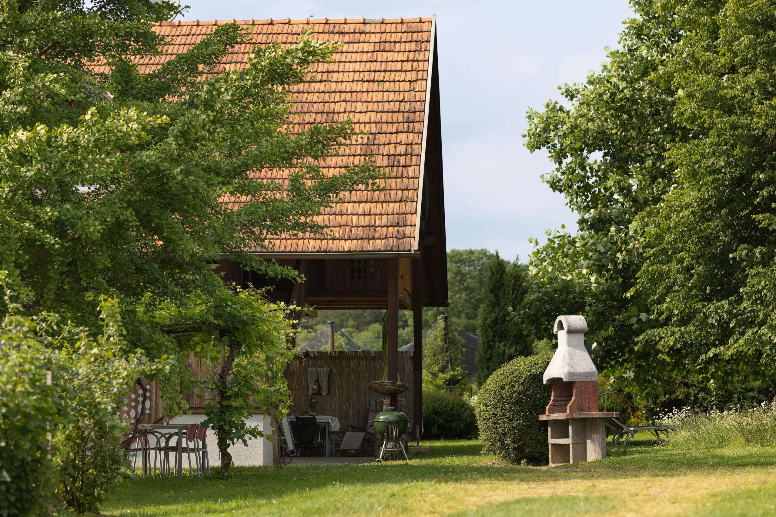 Zwei Gartengriller stehen in der grünen Wiese am Ferienhaus mit großen, schönem Baumbestand.