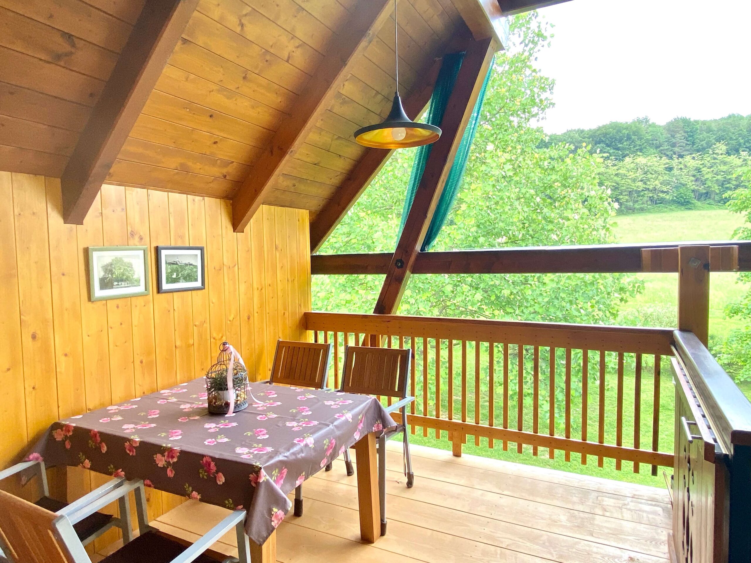 Diese Wohnung verfügt über einen großen Balkon aus Holz mit Tisch und Stühlen und einen umwerfenden Blick bis zum Waldrand.