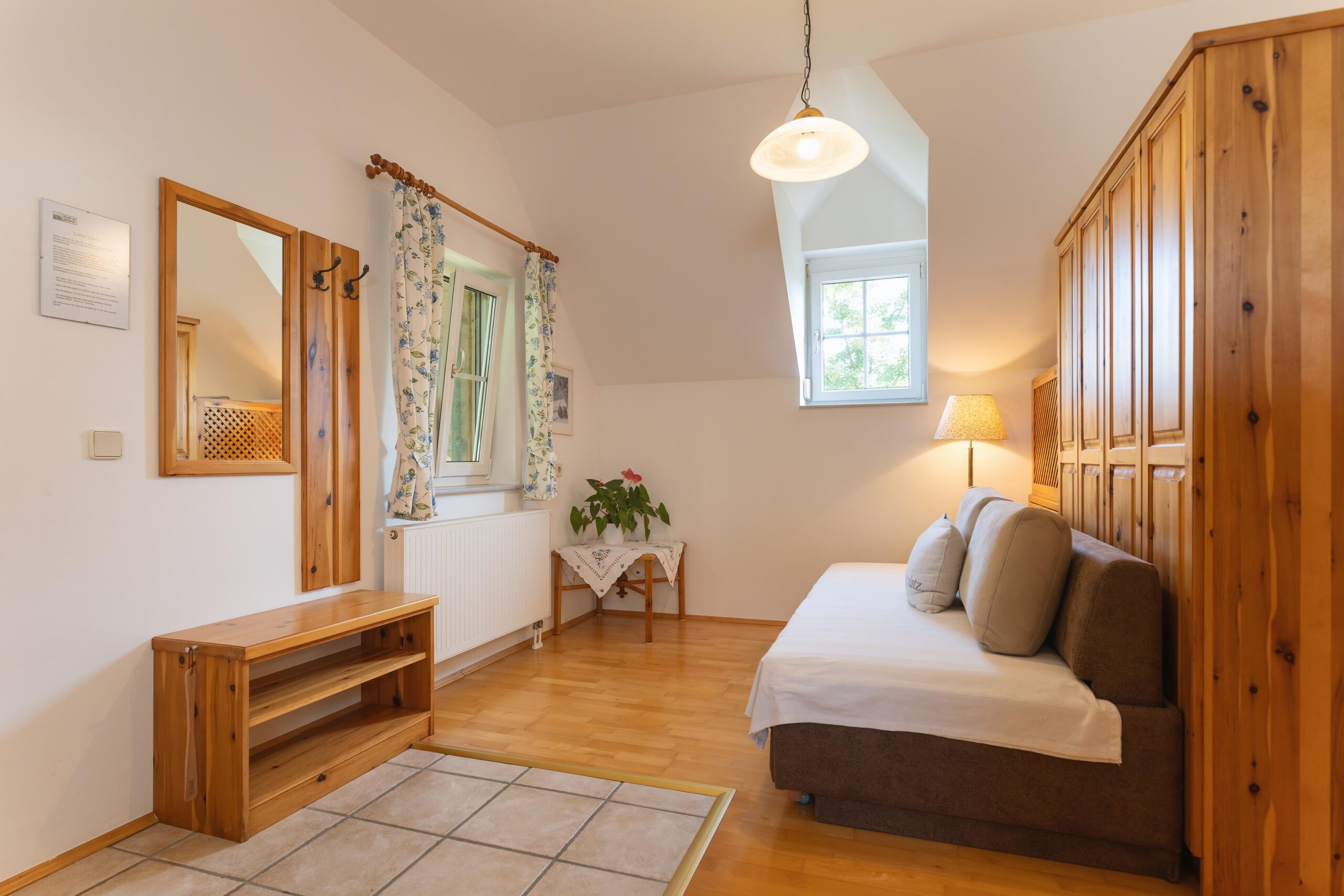 Der Wohnbereich in dieser Ferienwohnung bietet ein Sofa, eine Garderobe, einen großen Holzschrank und viel Tageslicht durch die Fenster. Ideal für einen entspannten Aufenthalt.